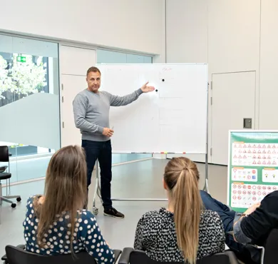 Tre elever modtager teoriundervisning af en koerelaerer i HandicapBilistCentrets specialkoereskole.